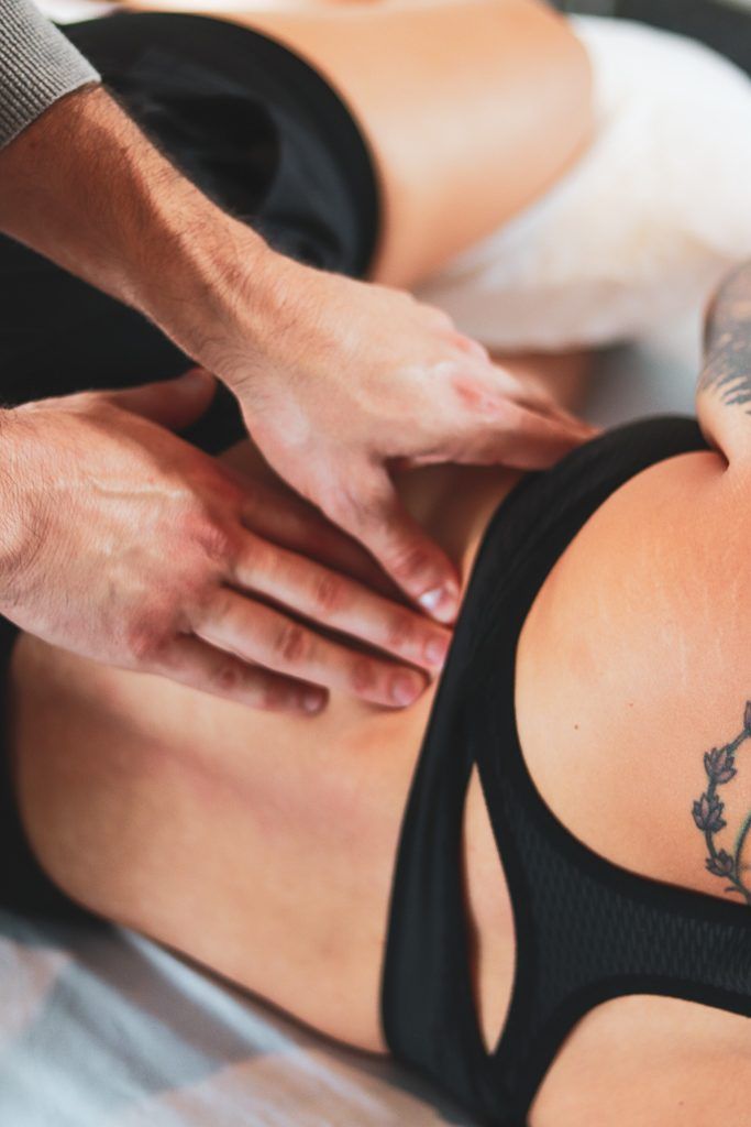 Close-up of Ryan Caputi's hands doing Rolfing work along a client's hip