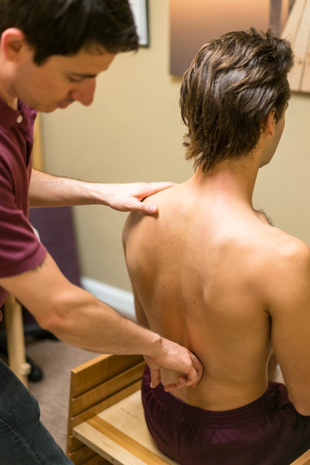 Ryan Caputi seated beside a client, doing hands-on Rolfing work on their back